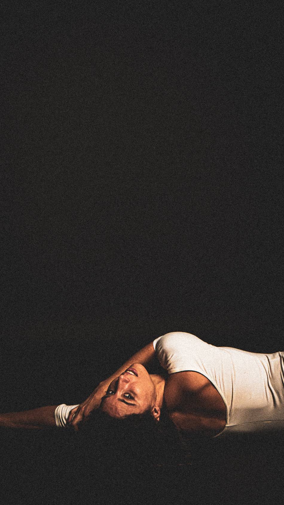 Dancer inverted mid-laugh under hard side light