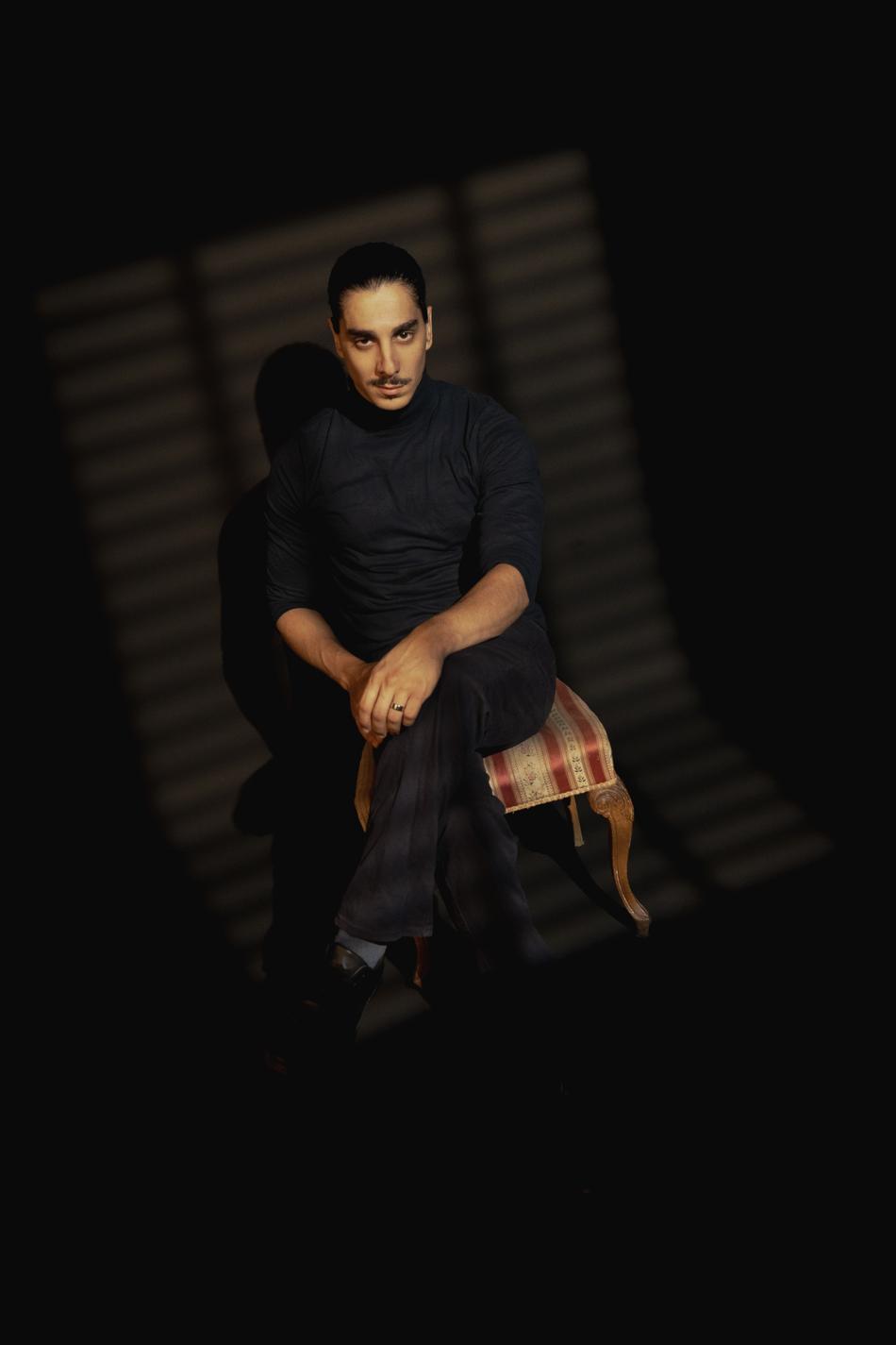 Actor seated on an antique chair, striped venetian-blind light