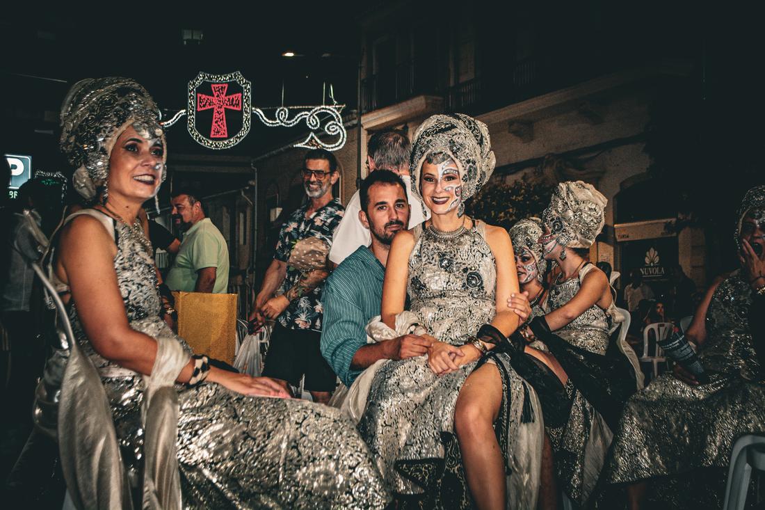 Woman in silver costume seated among the crowd