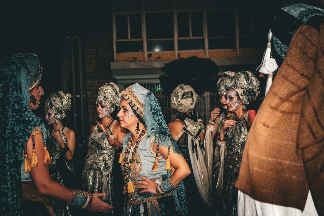 Group in teal and silver costume with tassels waiting at night
