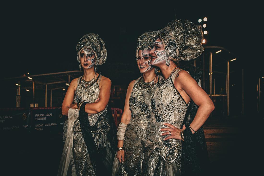 Three women in silver costume laughing on a Torrent street