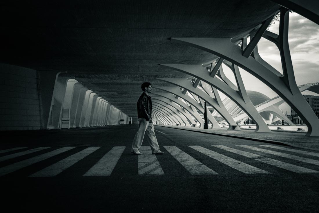Man walking beneath curved white arches