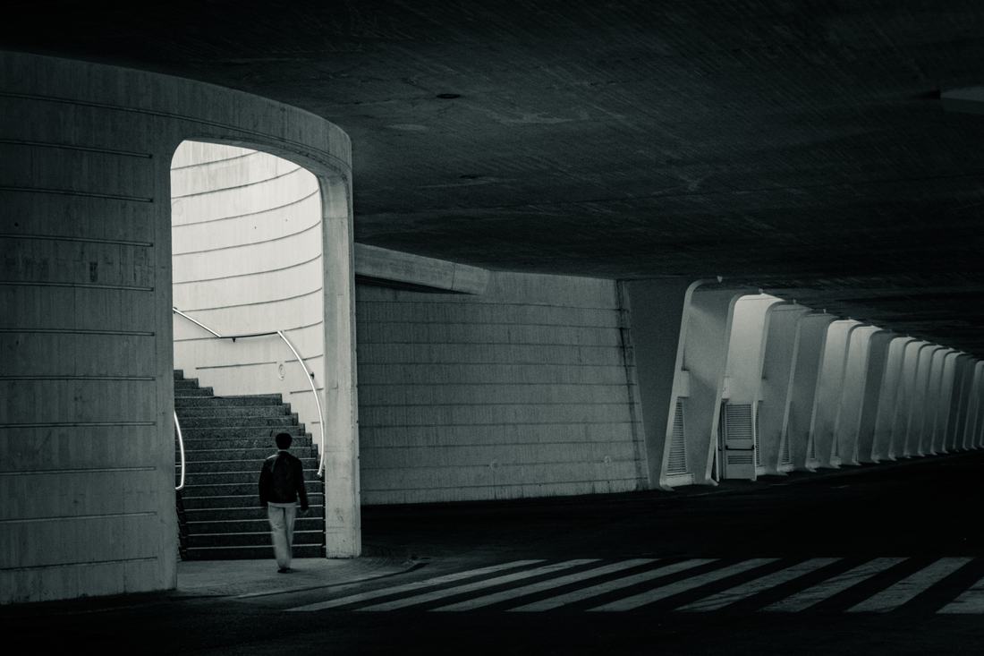 Man walking toward a lit stairway through an arch