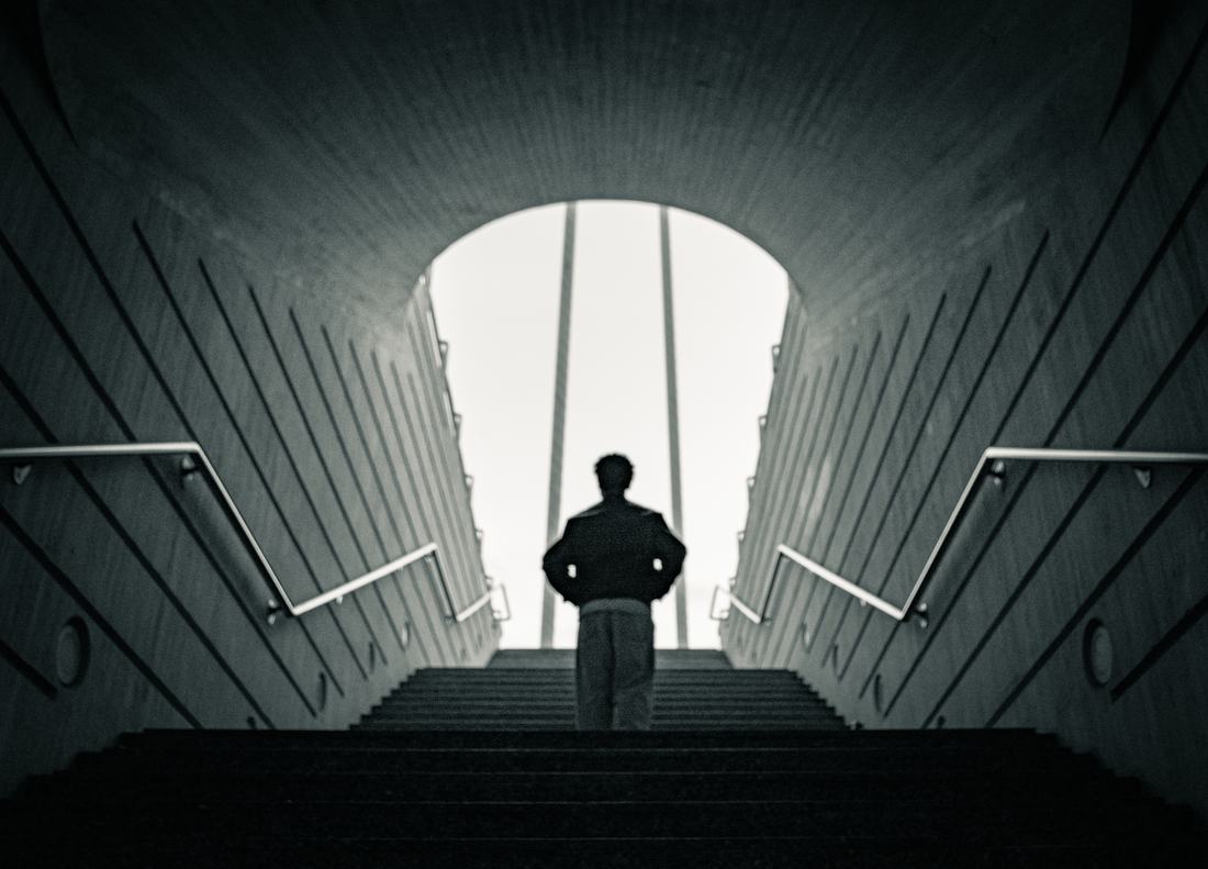 Silhouette of a man climbing stairs toward bright light