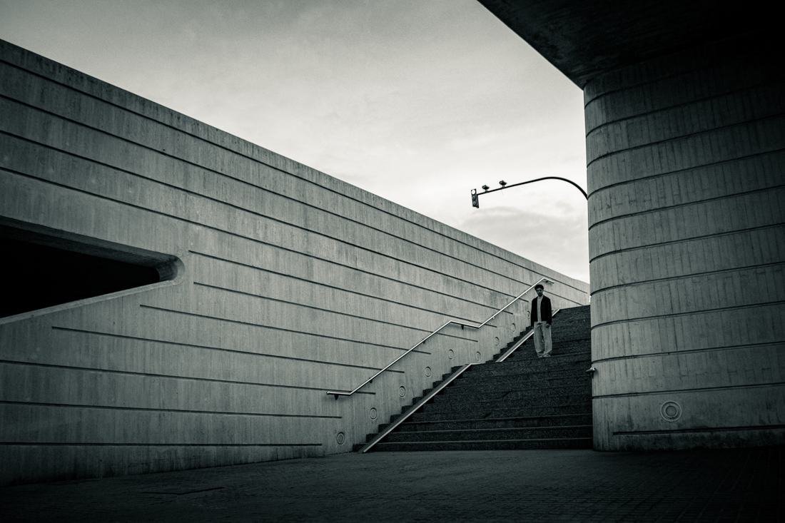 Small figure on a stairway dwarfed by concrete walls