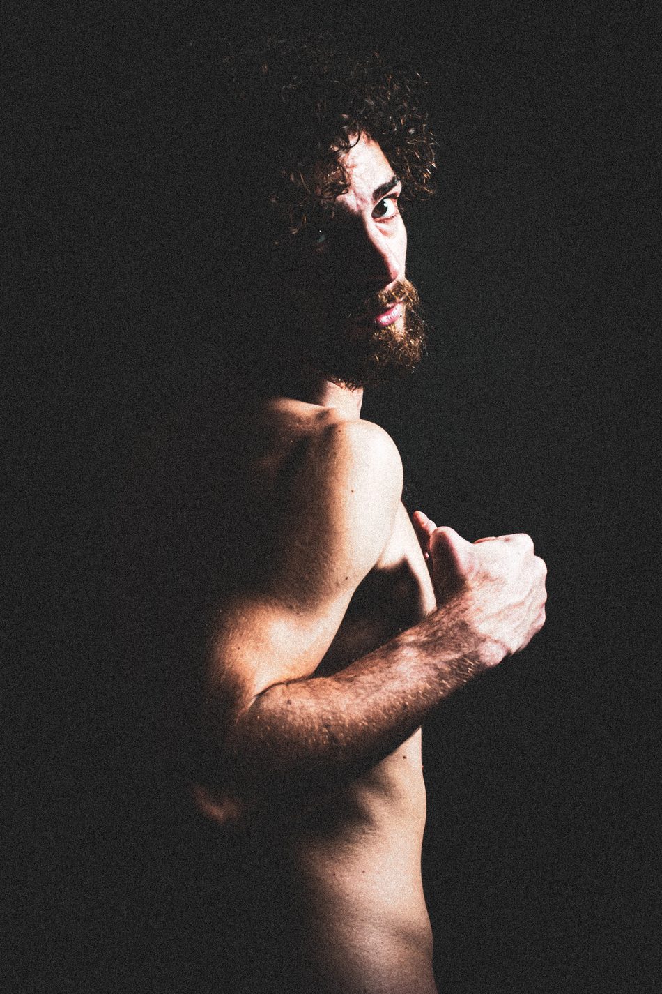 Man in profile glancing back over a raised shoulder, tense and alert