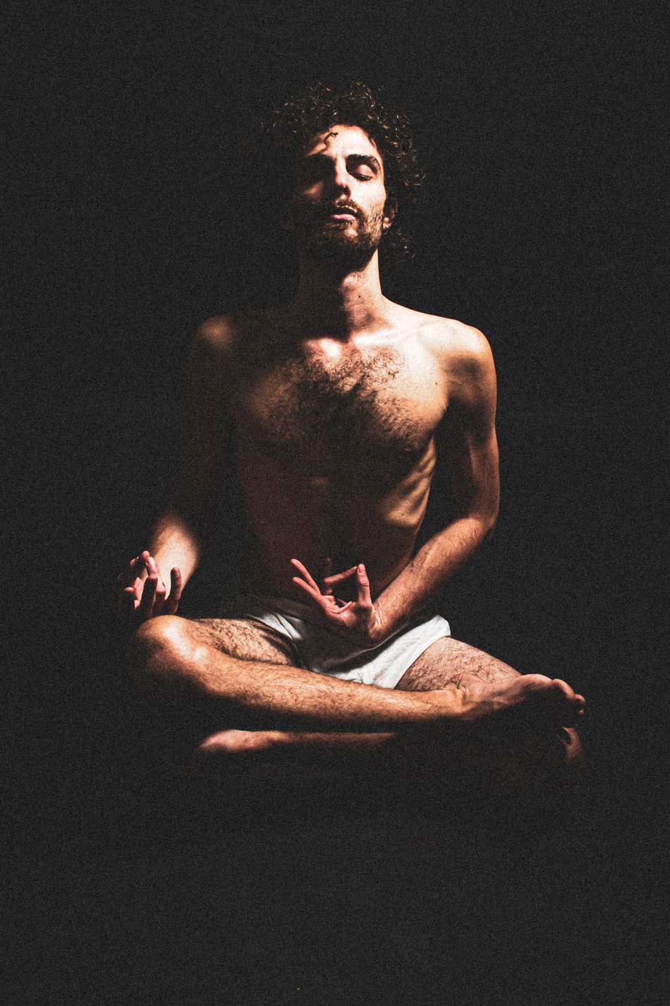 Man seated cross-legged in a meditative mudra, eyes closed